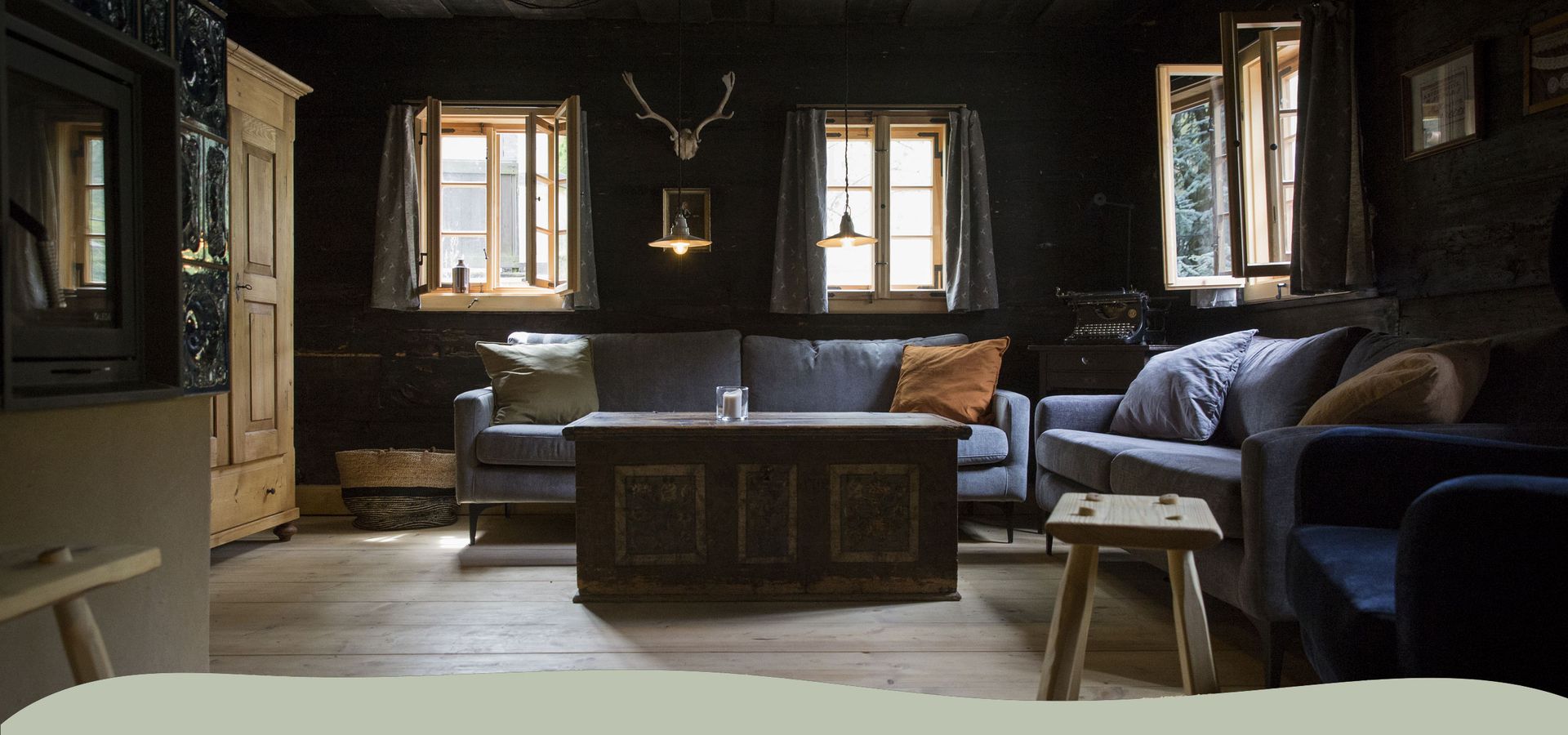 Historische Blockstube im Elbschifferhaus mit dunklem Holz, Sofas und alter Truhe als Couchtisch