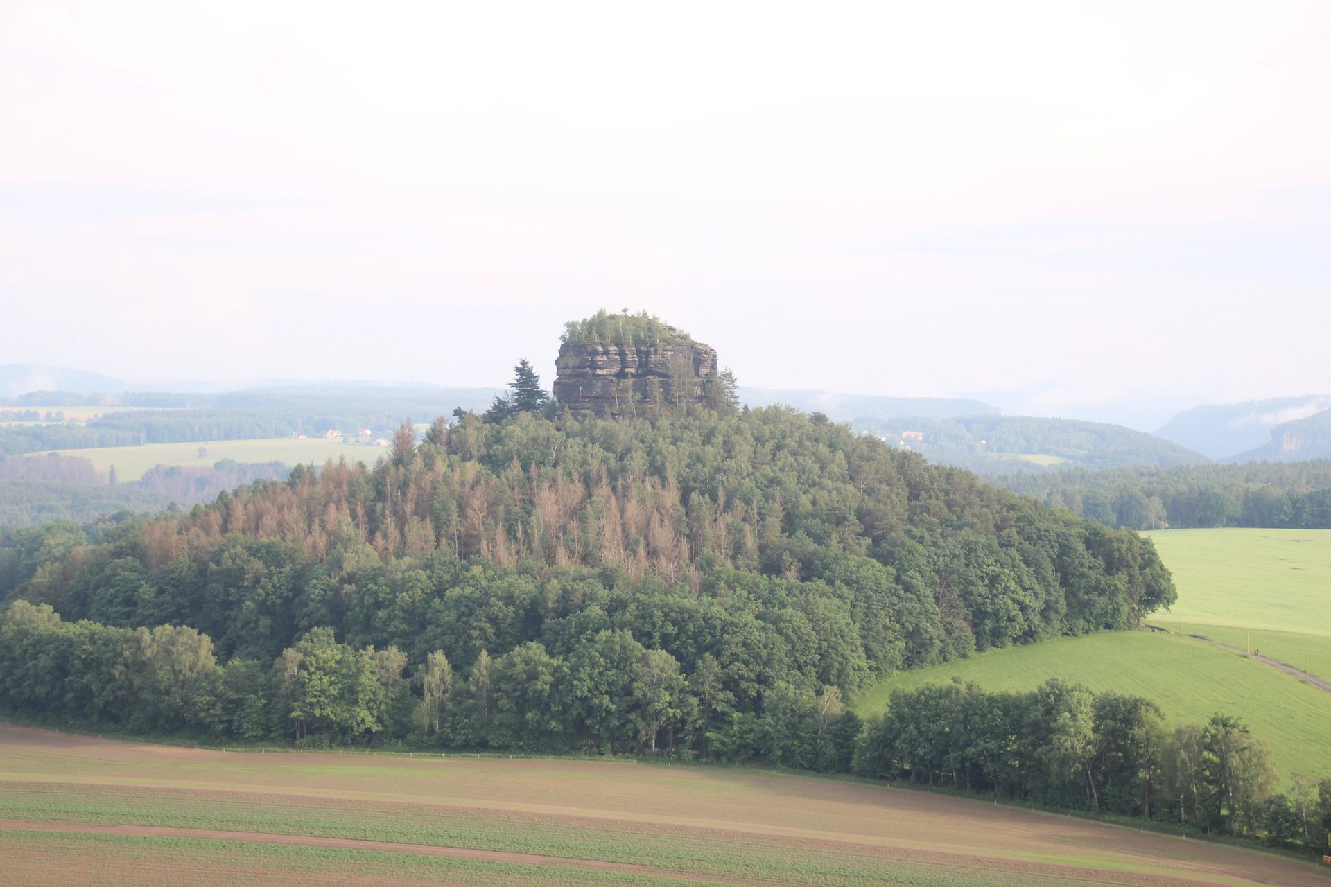 Der Tafelberg Kaiserkrone bei Reinhardtsdorf über Feldern im Dunst